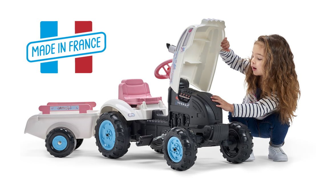 petite fille soulevant le capot de son tracteur rose